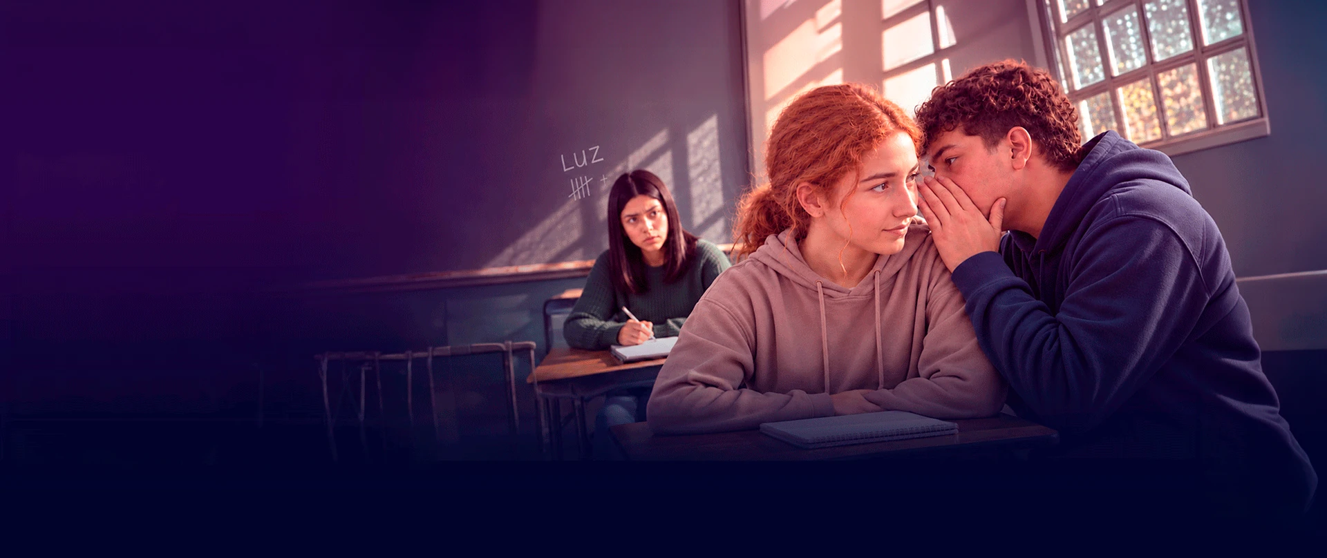 Un alumno le habla al oído a una compañera mientras otra alumna observa desde su banco